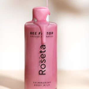 Roze Bee Factor Glow Up Roseta-fles met glinsterende bodymilk die over de dop loopt.
