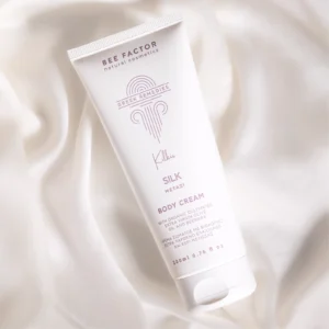 Witte tube Bee Factor Silk Soft-Touch-bodycrème op licht geplooide stof.